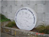   Small round granite sculpture with inscriptions titled 