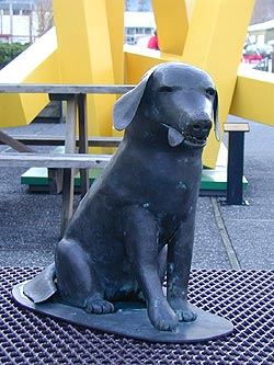 Metal sculpture of a seated dog titled 