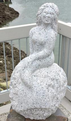 Medium-size stone sculpture of a mermaid sitting on a rock titled 